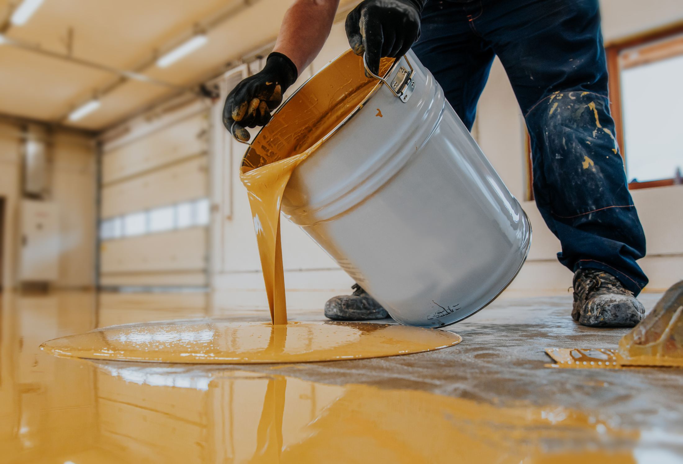 Coating material being poured onto prepared concrete